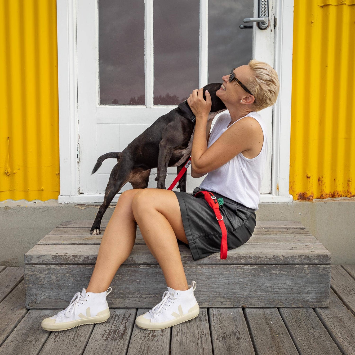 Woman and dog with red dog lead and poop bag holder